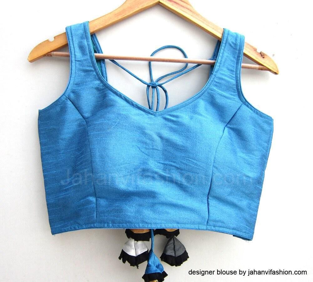 Blue sleeveless saree blouse with open back, tied halter neckline, and tassel accents