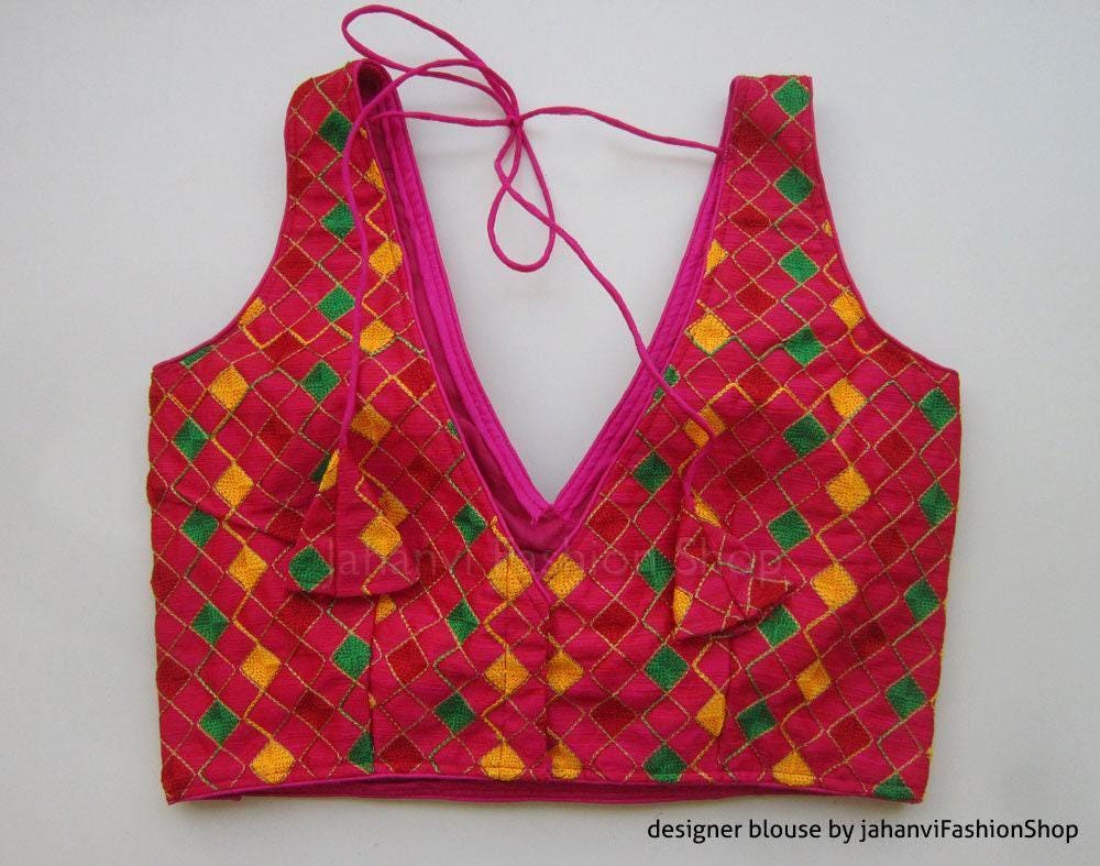 Magenta sleeveless saree blouse with deep V back, drawstring bow tie, geometric green and yellow embroidery