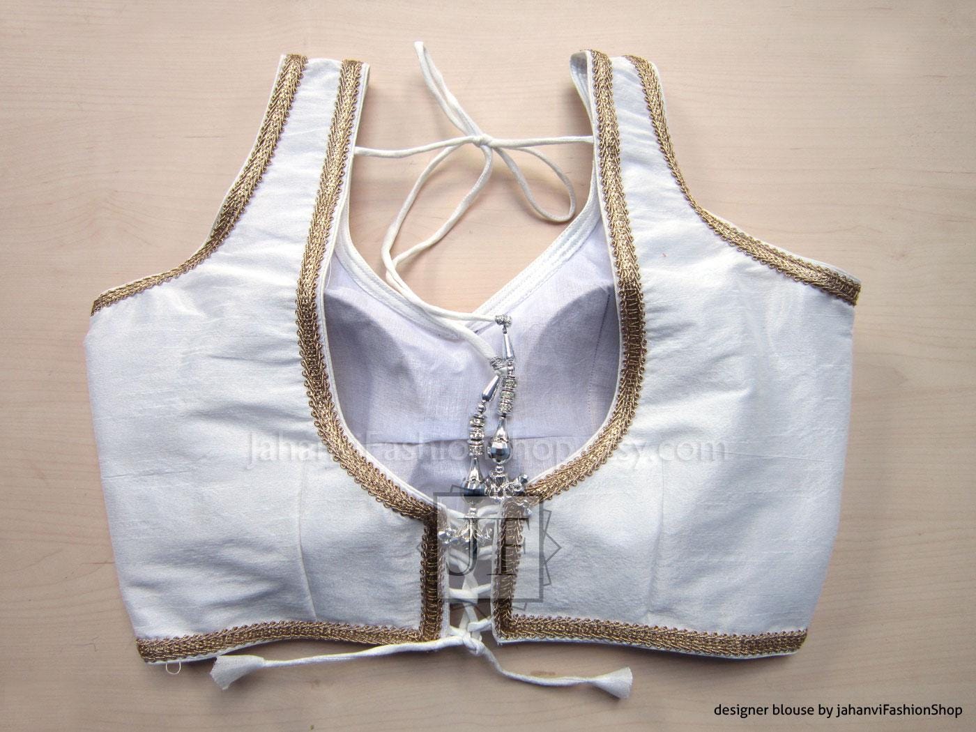 Backless white sleeveless saree blouse with golden lace trim and tie-neck strings