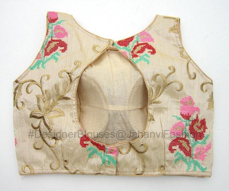 Back view of sleeveless boat-neck blouse with open back and hook closure; cream/gold embroidery
