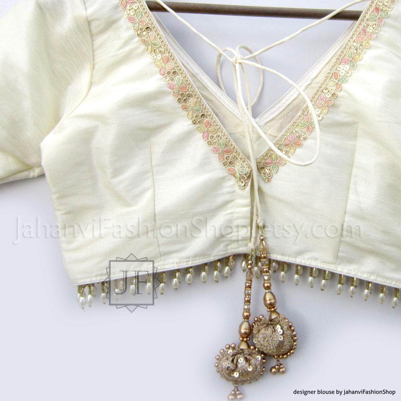 White V-neck saree blouse crop top with gold trim and tie-front neckline, beaded fringe.