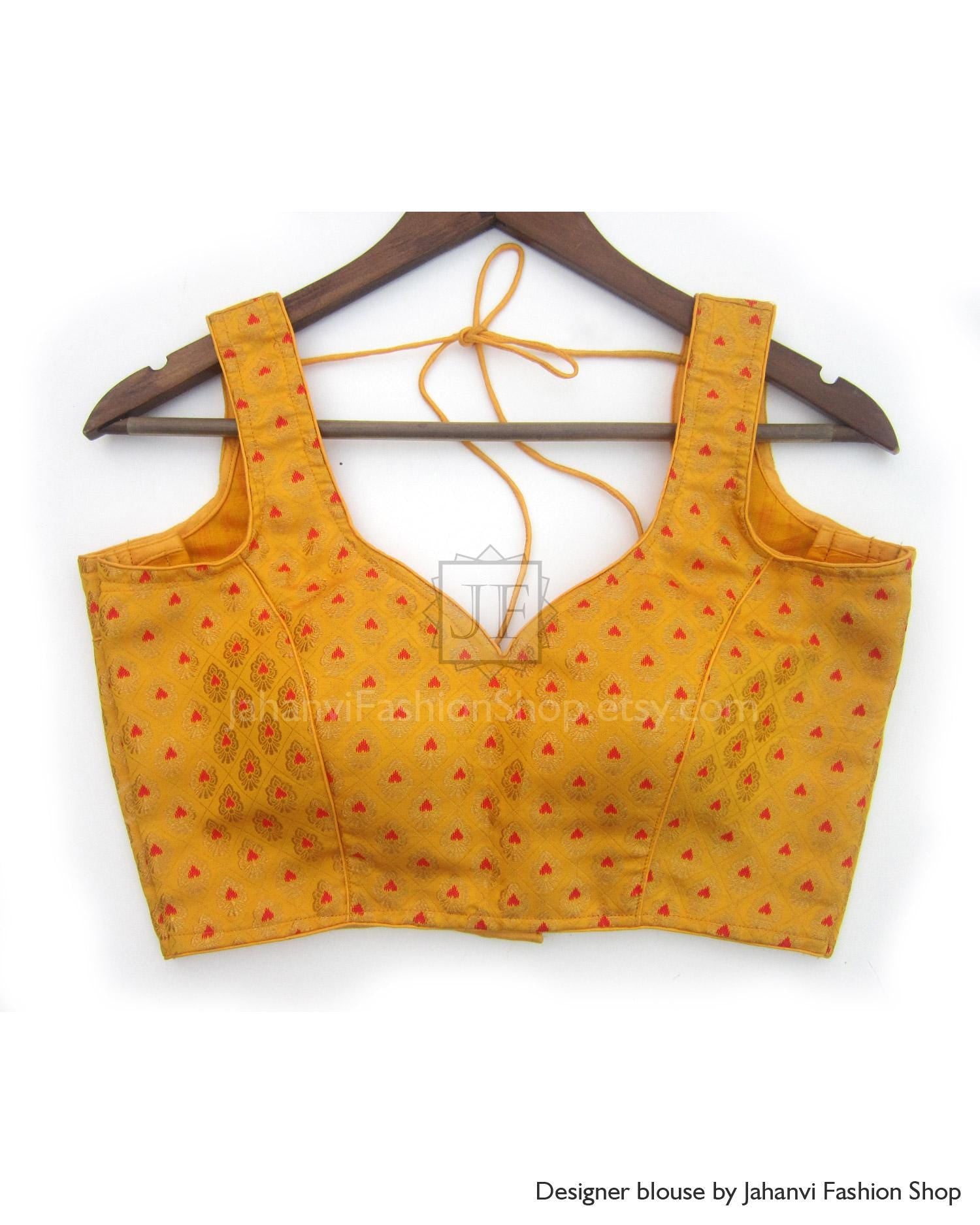 Orange embroidered sleeveless blouse with V neckline and open back tie, on a hanger
