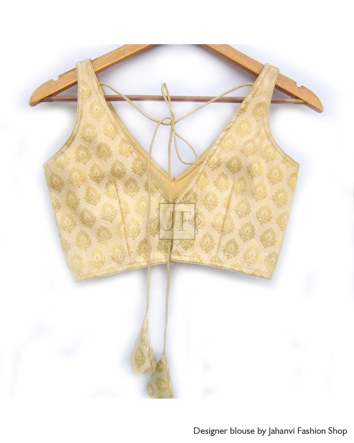 Gold patterned sleeveless saree blouse with deep back V, tie strings, on wooden hanger